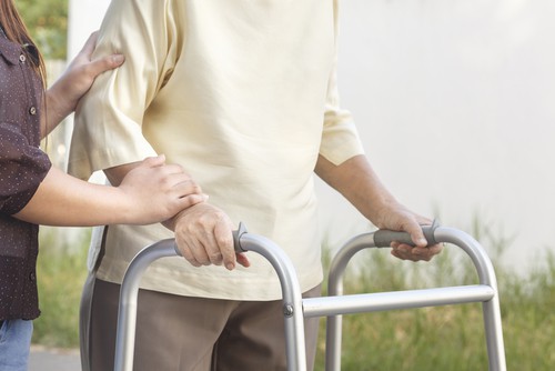 Elderly using a walker with caregiver